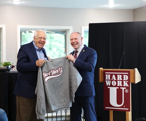 Dr. Johnson gifts Dr. Newbury a "Hard work U" sweatshirt